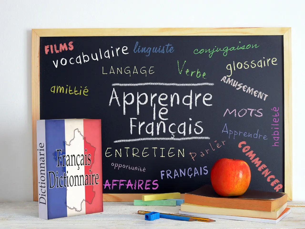 French language learning concept with chalkboard full of vocabulary words and a Français dictionary, symbolizing translation and education.