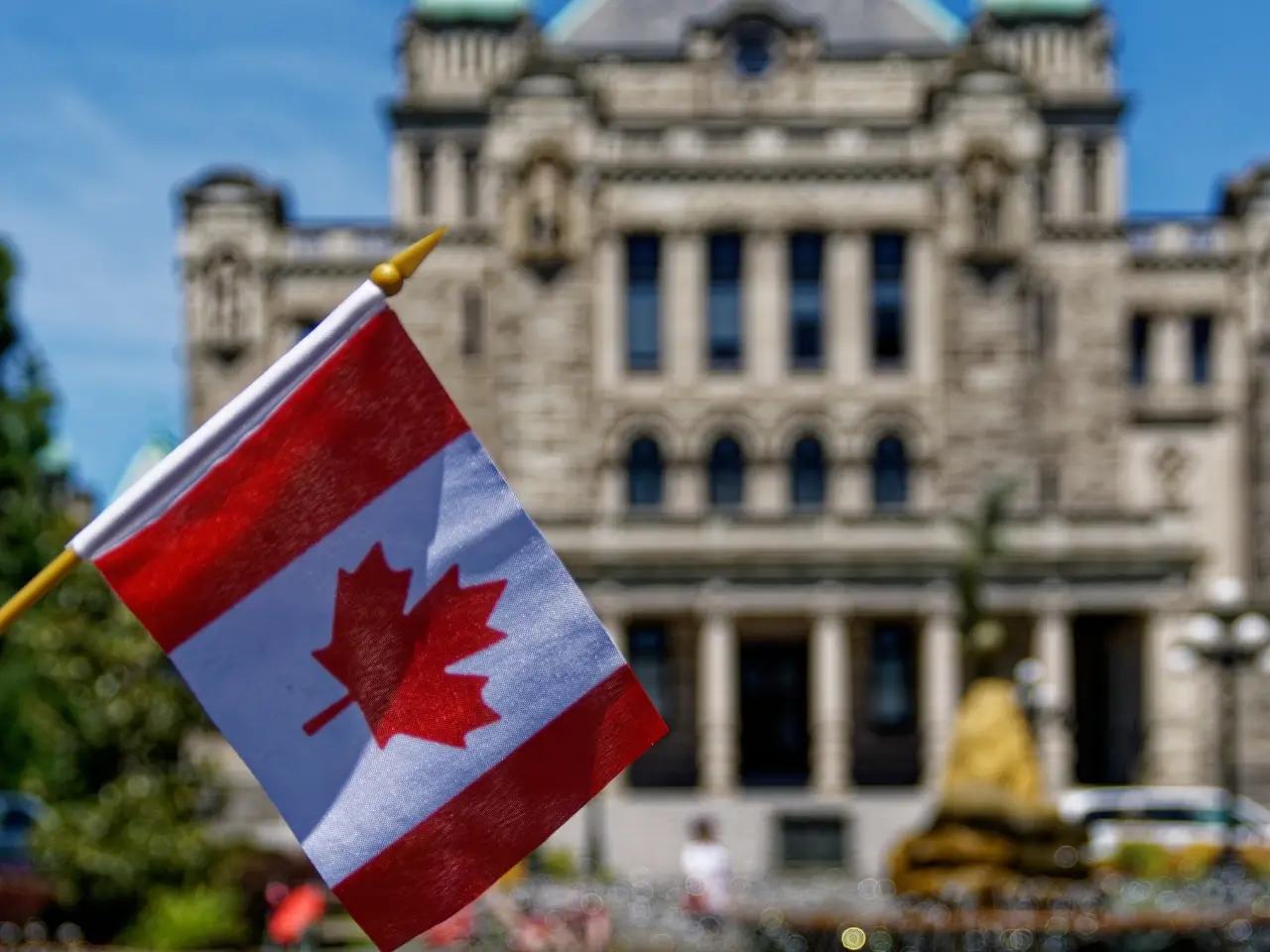 Canadian flag in front of a historic government building, symbolizing official immigration, legal, or translation services in Canada.