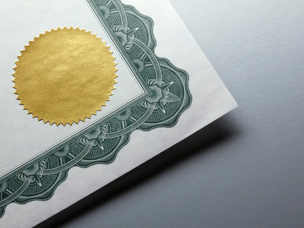 Close-up of a formal certificate corner featuring a gold embossed seal and ornate green border, symbolizing authenticity and official document validation.
