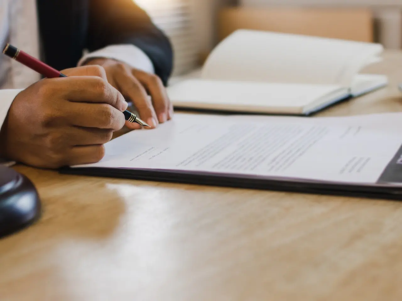 A person in formal attire signing an official document with a fountain pen, symbolizing legal authorization, certified services, or contract validation.