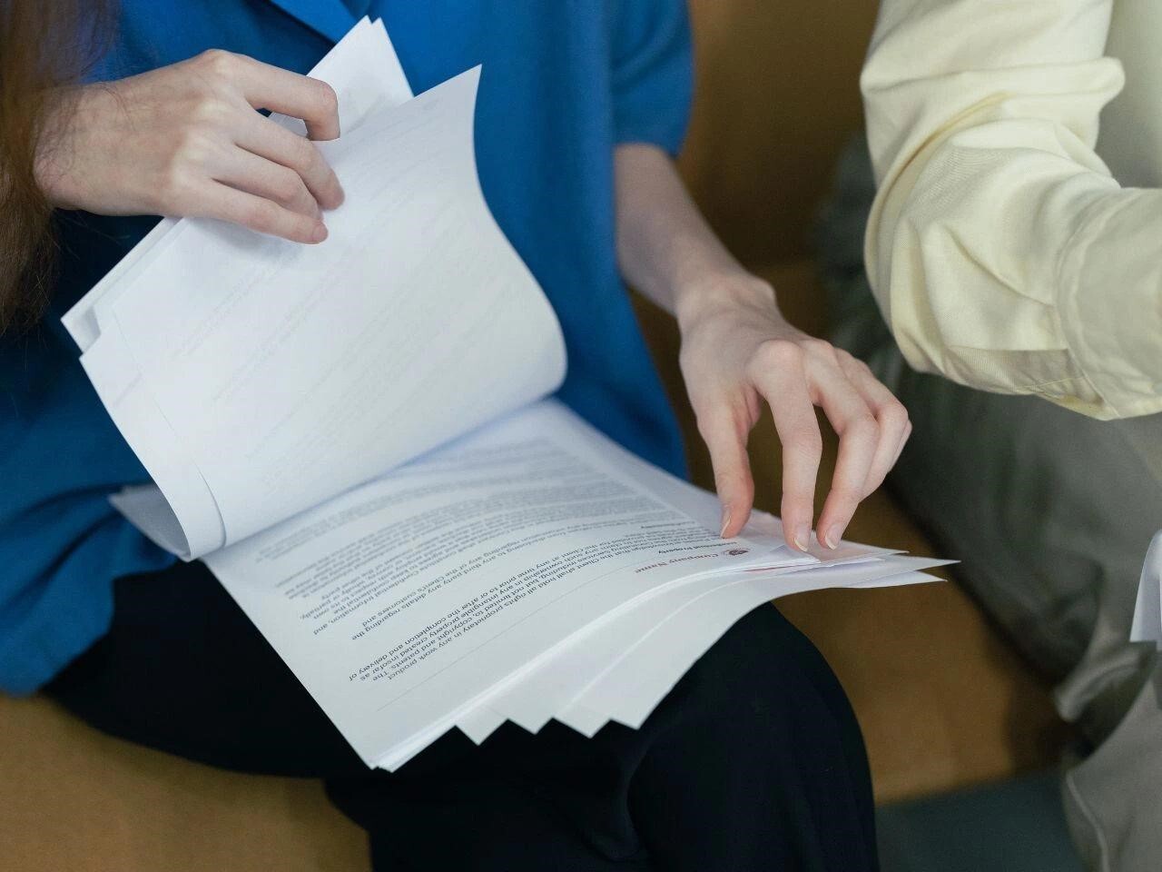 Person flipping through a stack of official documents, representing the review process before submitting certified translations.