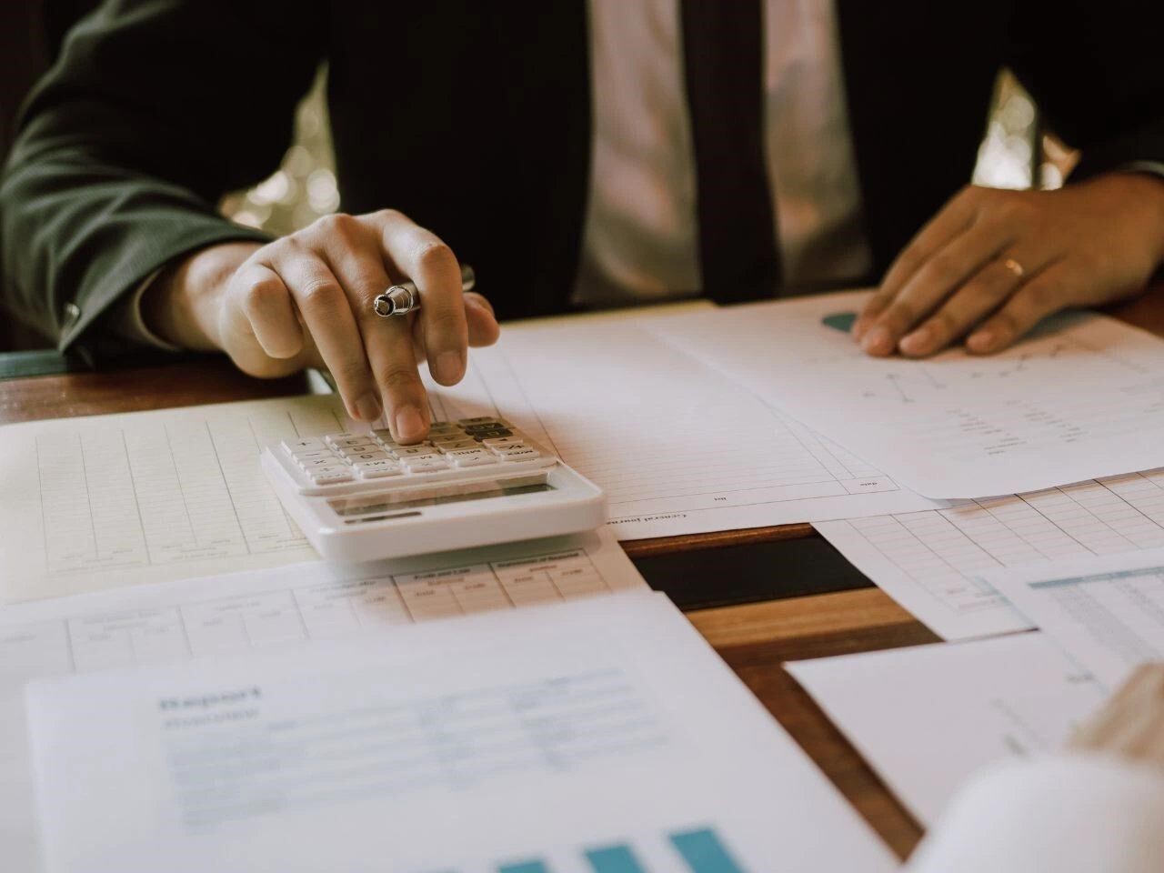 Business professional using a calculator while reviewing documents, representing cost estimation and billing for certified translation services.