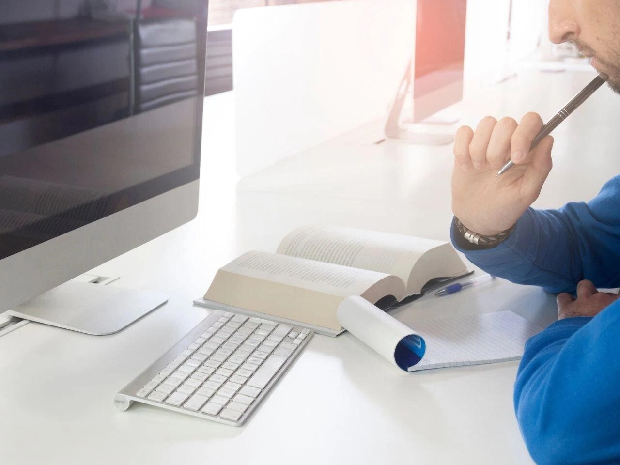 Translator working at a computer with open reference books and notes, representing focus and precision in certified document translation.