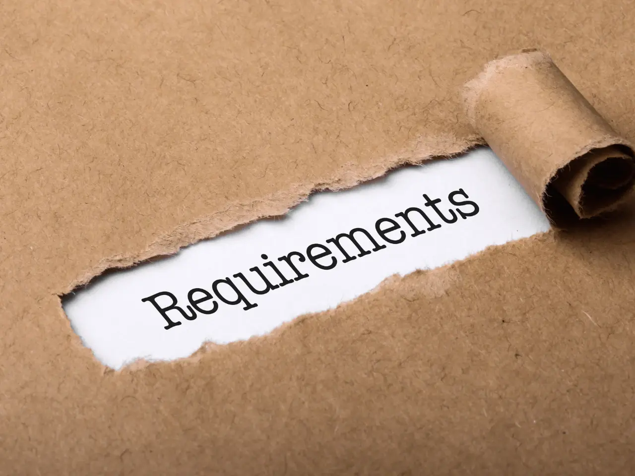 Torn kraft paper revealing the word “Requirements,” symbolizing the criteria needed to obtain a birth certificate.