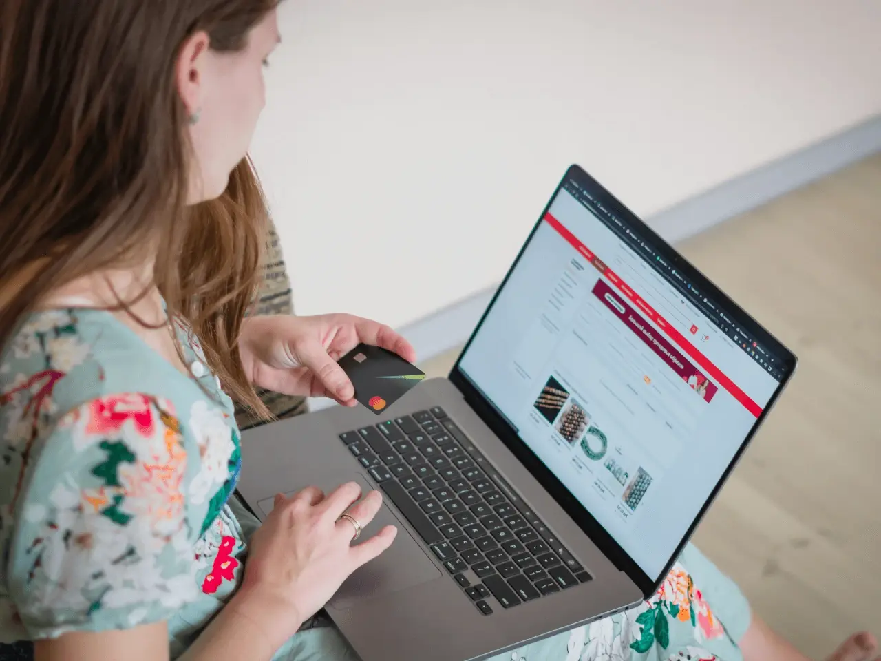 Woman holding a bank card while using a laptop for an online application or document order.