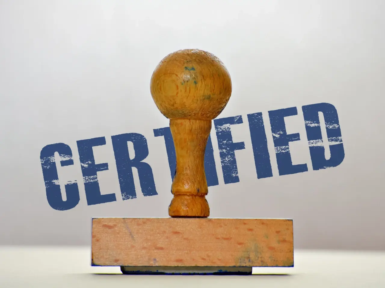 Wooden stamp with the word “CERTIFIED” in bold blue letters, representing official approval of translated documents.