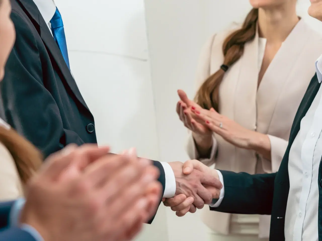 Business professionals shaking hands while colleagues applaud, symbolizing successful collaboration on certified document translation services.