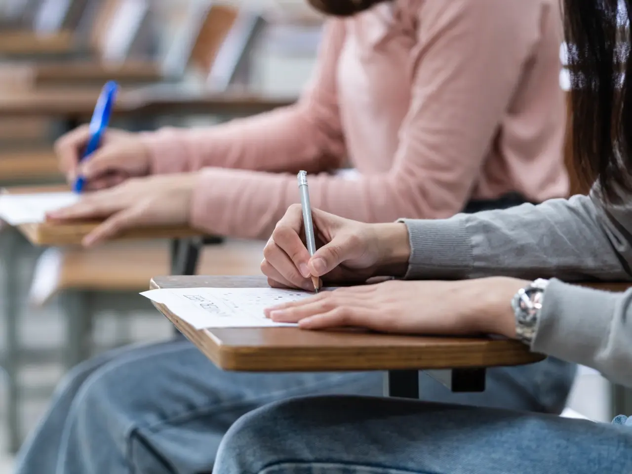 Students writing on paper during an exam, representing translation services for academic records, diplomas, and certificates.