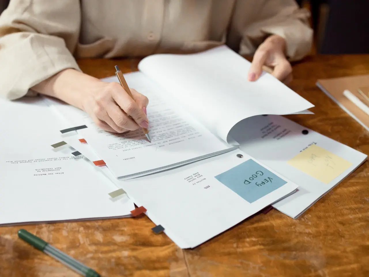 Person reviewing and marking official documents with sticky notes and tags, representing the editing and verification process in certified translation services.