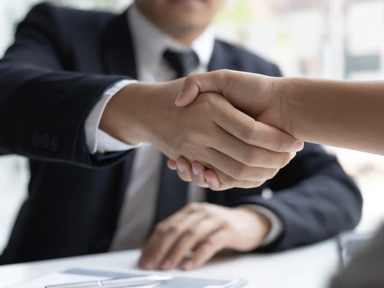 Close-up of a handshake between two professionals, representing trust and agreement in certified translation services.