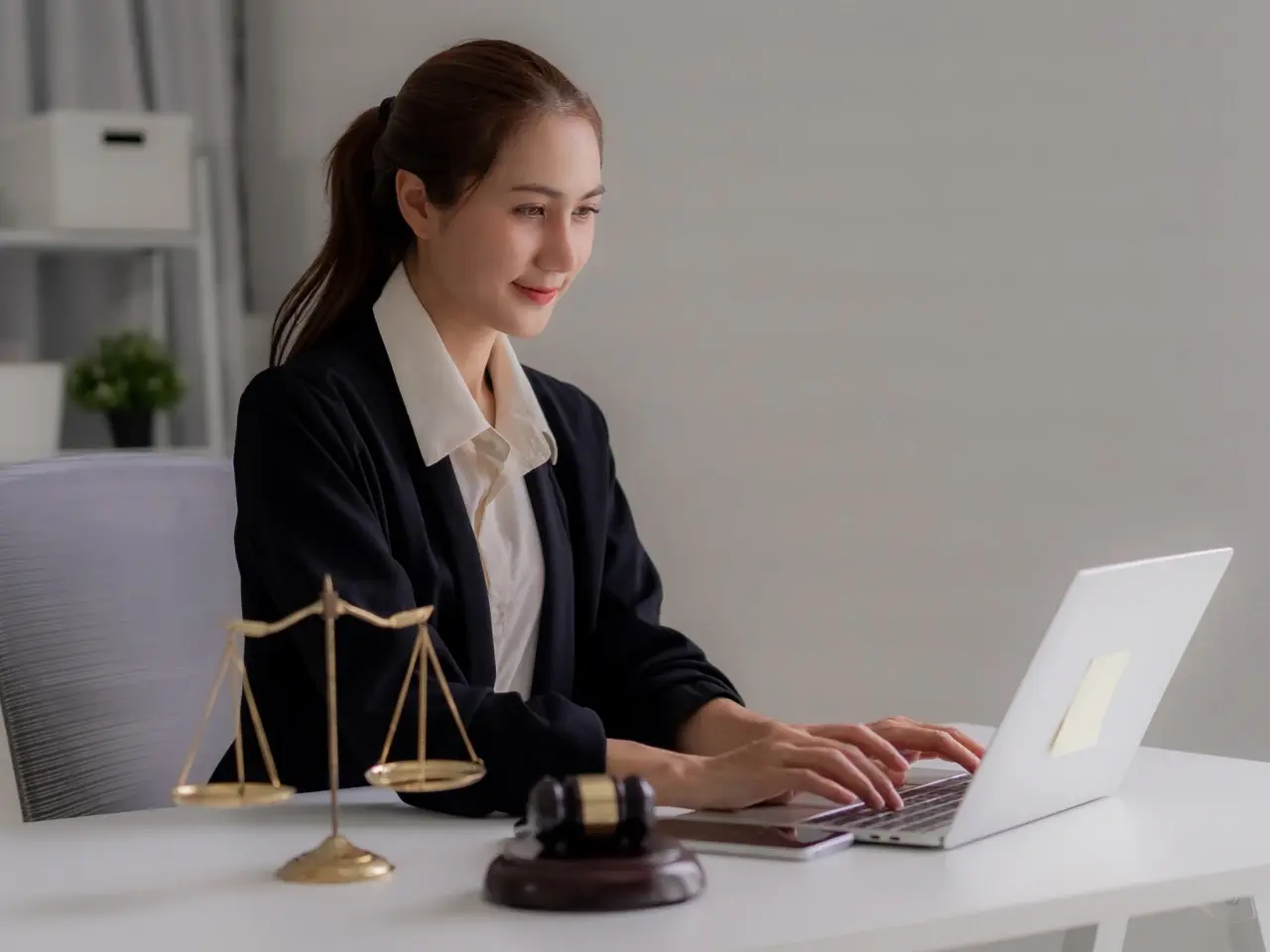 Woman reviewing documents on a laptop beside a gavel, representing different types of powers of attorney in Canada.