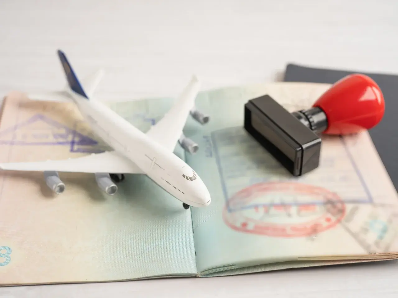 Open passport with stamps, airplane, and a rubber stamp symbolizing international document use.