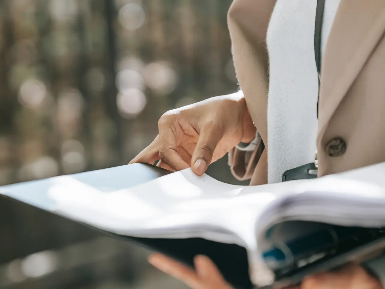 Close-up of a person in formal attire holding a large stack of clipped documents, symbolizing the preparation required for document legalization and authentication in Canada.