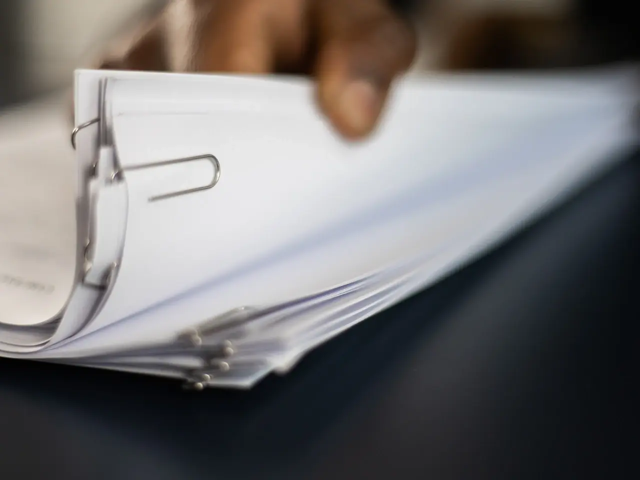 Hand holding a stack of clipped documents, representing bundled translated paperwork prepared for submission or certification.
