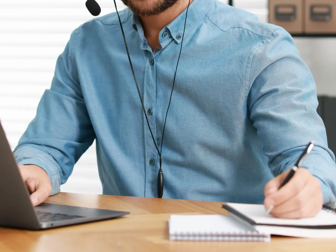 Customer support representative with a headset writing notes during an online consultation, representing assistance with certified translation inquiries.