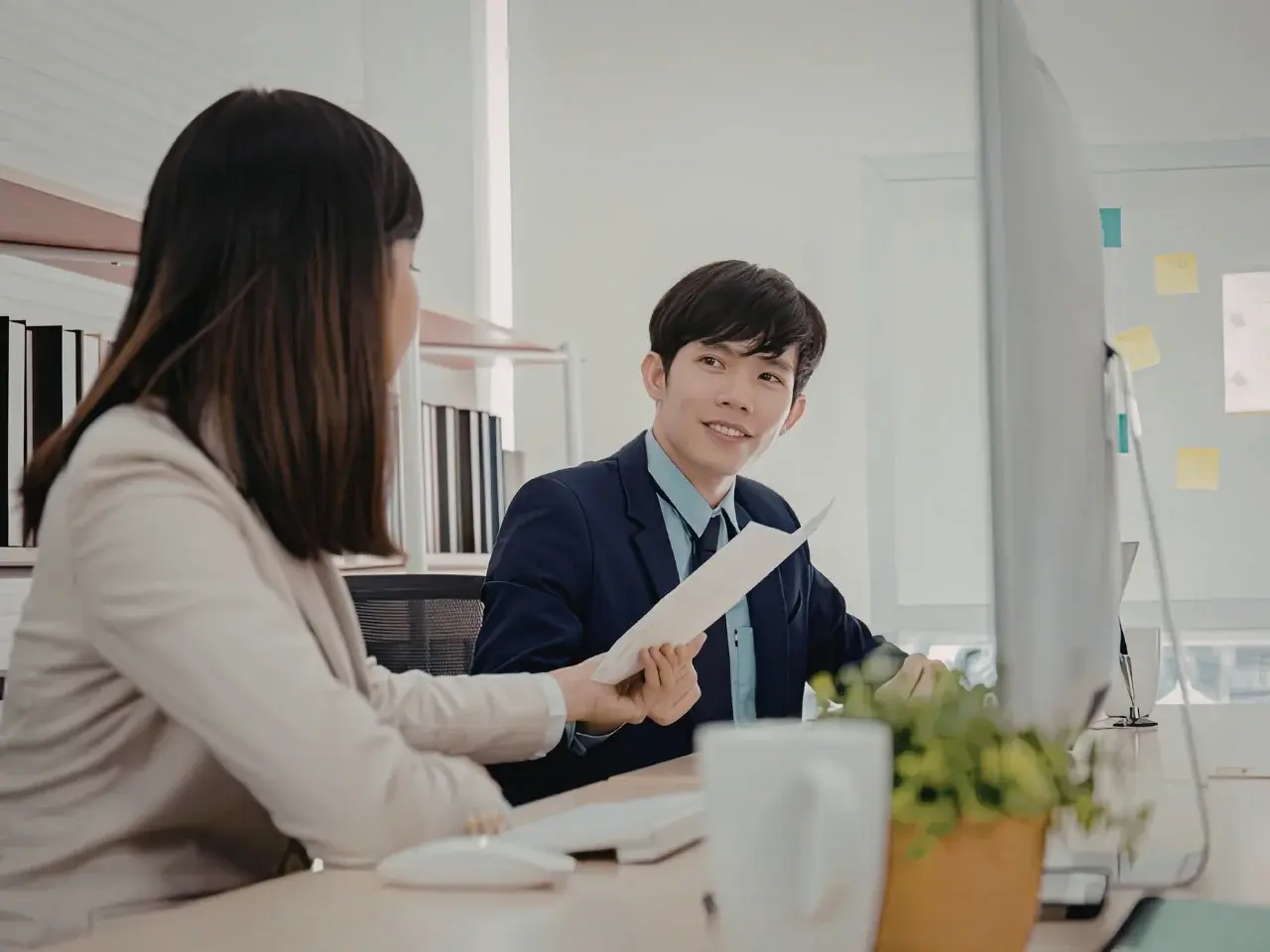 Two professionals in a bright boardroom discussing a French-language contract.
