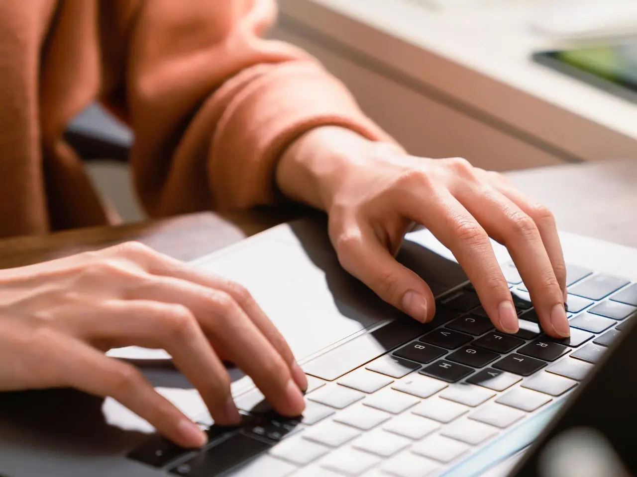 Close-up of hands typing on a laptop keyboard, representing the process of creating certified document translations.