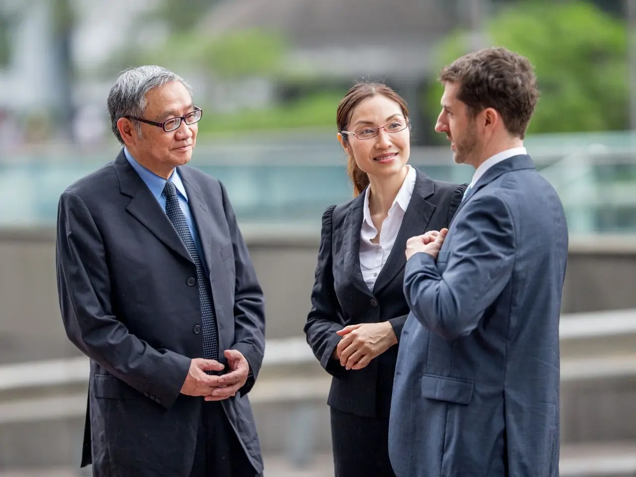 Three business professionals having a conversation outdoors, representing multilingual communication supported by certified translation or interpretation services.