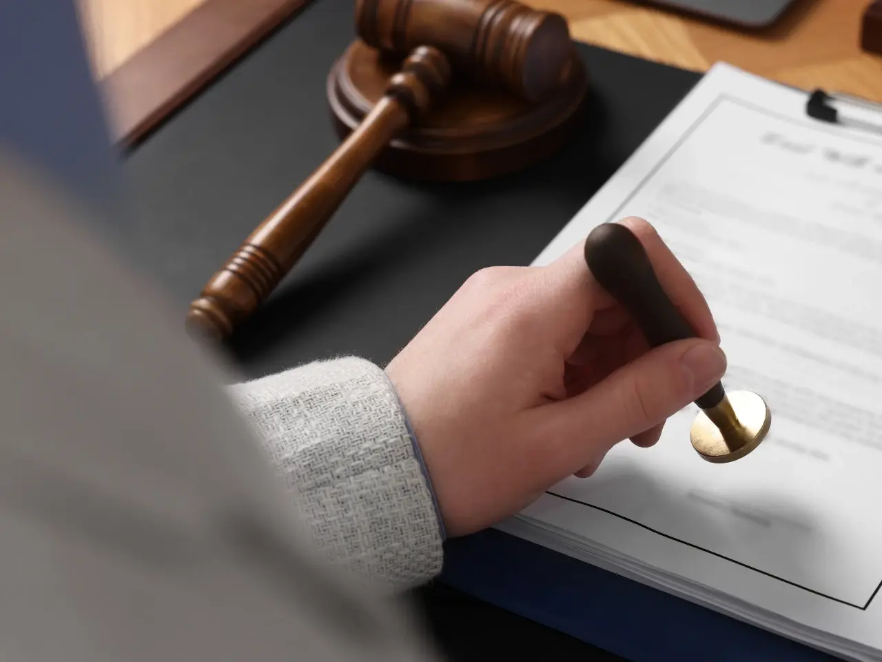 Close-up of a person using a seal stamp on legal documents symbolizing notarization or official approval.