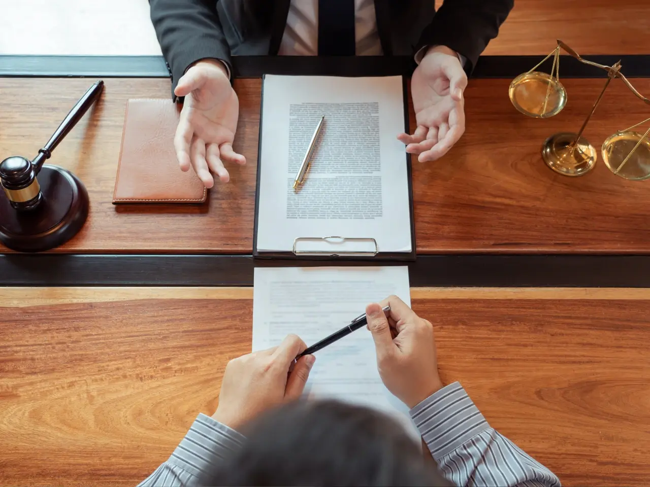 Two people discussing legal documents at a table with a gavel and scales of justice, symbolizing notarization, legalization, or legal consultation.