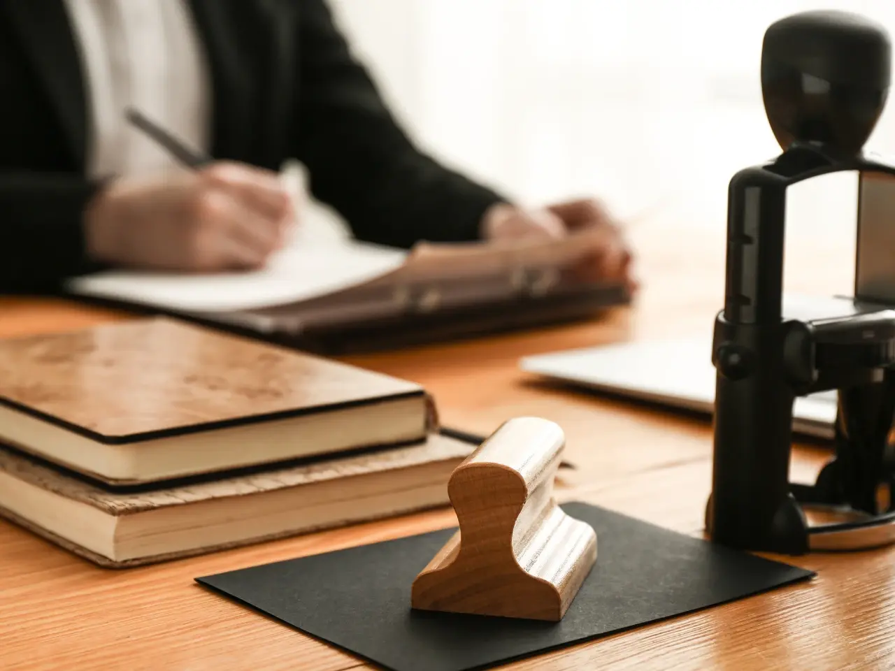Wooden notary stamp on a desk with legal books, symbolizing notarization or legal documentation services.
