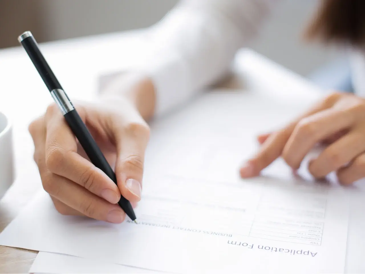 Hand signing an official document, illustrating how provincial and federal authorities issue apostilles in Canada.
