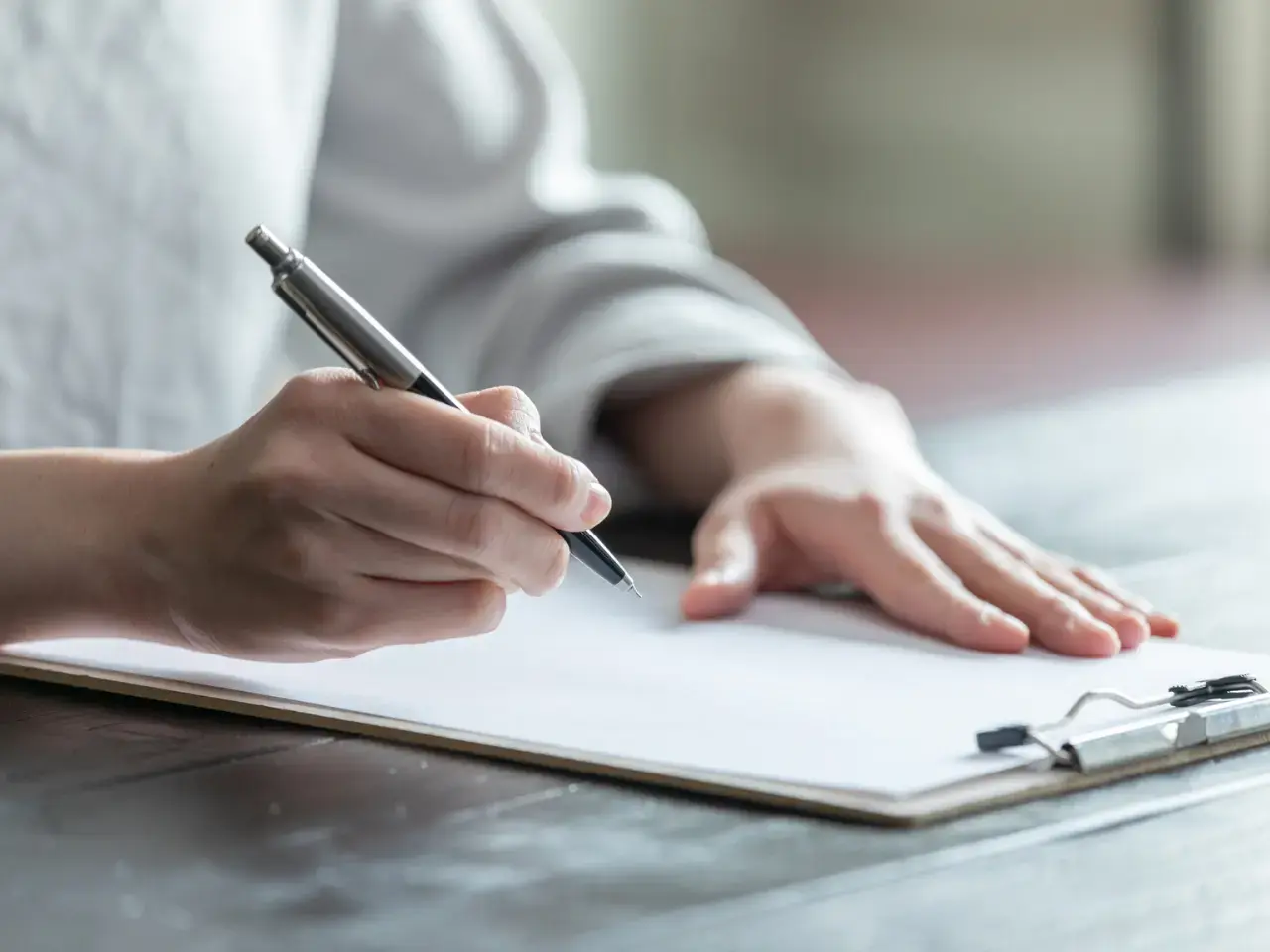 Person completing forms on a clipboard, illustrating eligibility requirements for individuals, corporations, trusts, and charities requesting a CRA residency certificate.