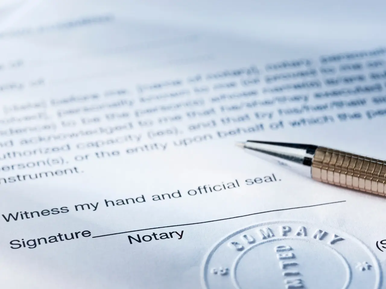 A close-up of a legal document with a metallic pen resting near a section labelled “Signature” and “Notary.” An embossed notary seal marked “COMPANY LIMITED” is partially visible, indicating that the document is in the process of being notarized or officially validated.
