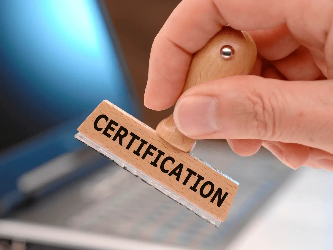 Close-up of a hand holding a wooden stamp with the word “CERTIFICATION” in bold black letters symbolizing receiving a certified Single Status Affidavit in Canada for marriage abroad.