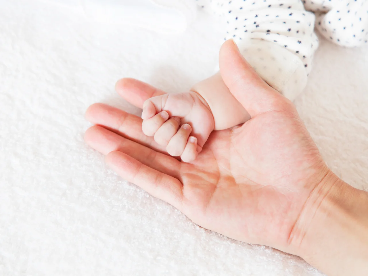 Parent holding a newborn baby’s hand, representing a child born abroad to a Canadian citizen.
