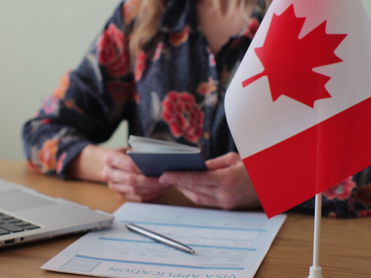 Person reviewing citizenship documents beside a Canadian flag.