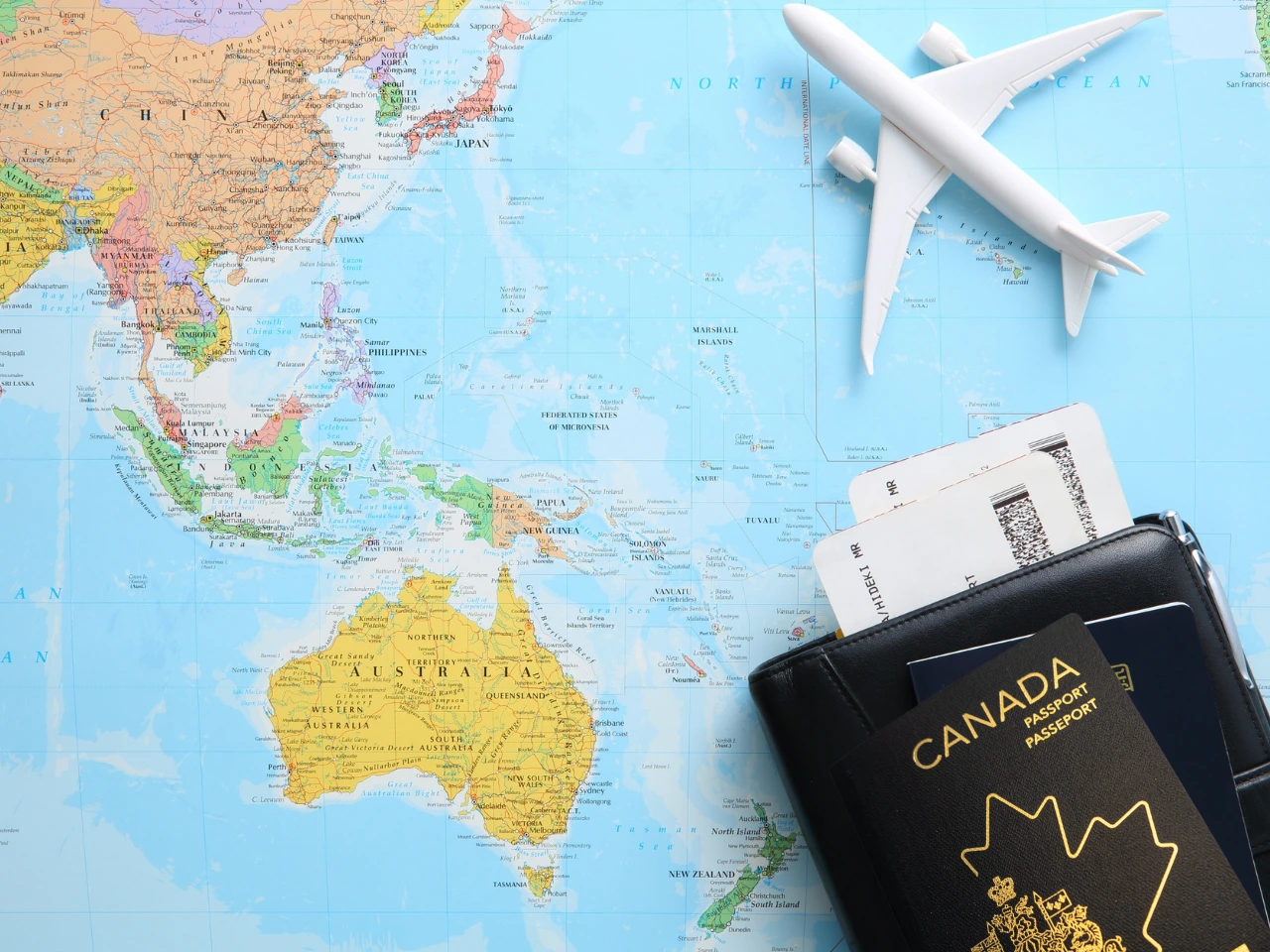 Canadian passport, world map, and airplane representing international travel for dual citizens.