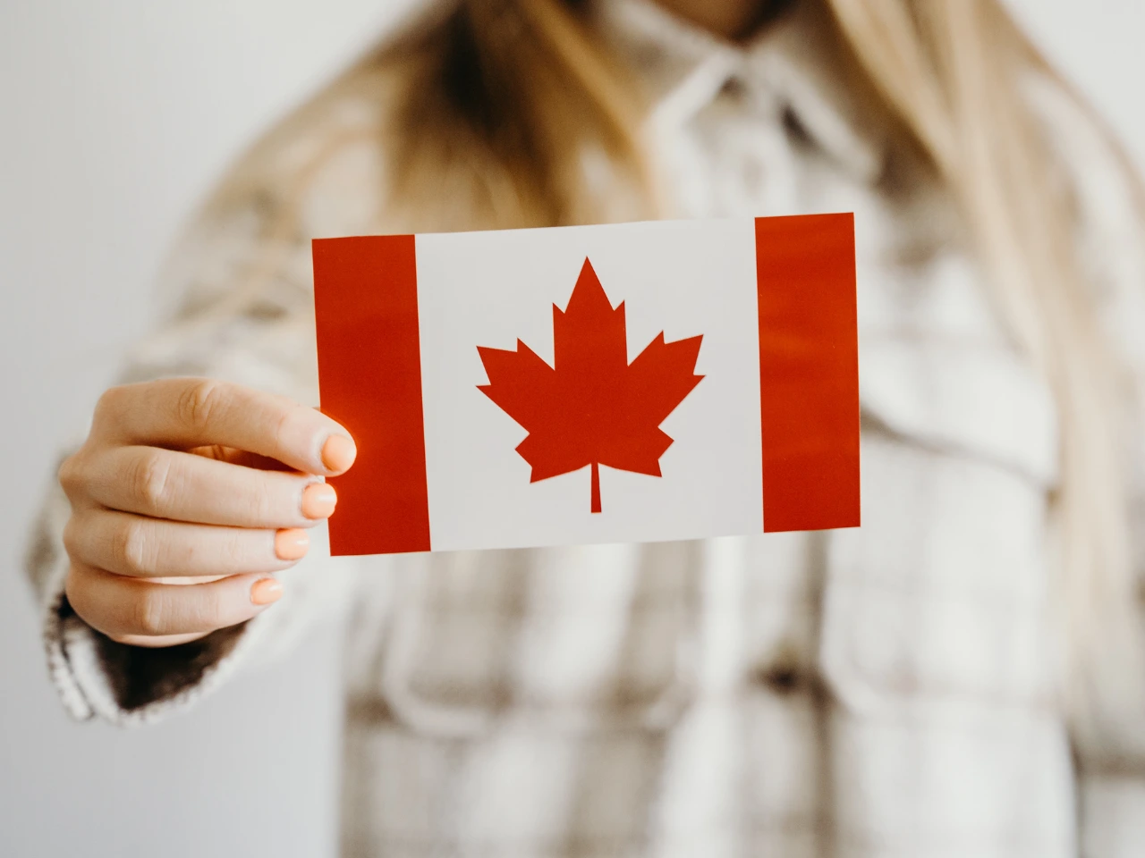 Person holding a Canadian flag representing Canadian citizenship status.
