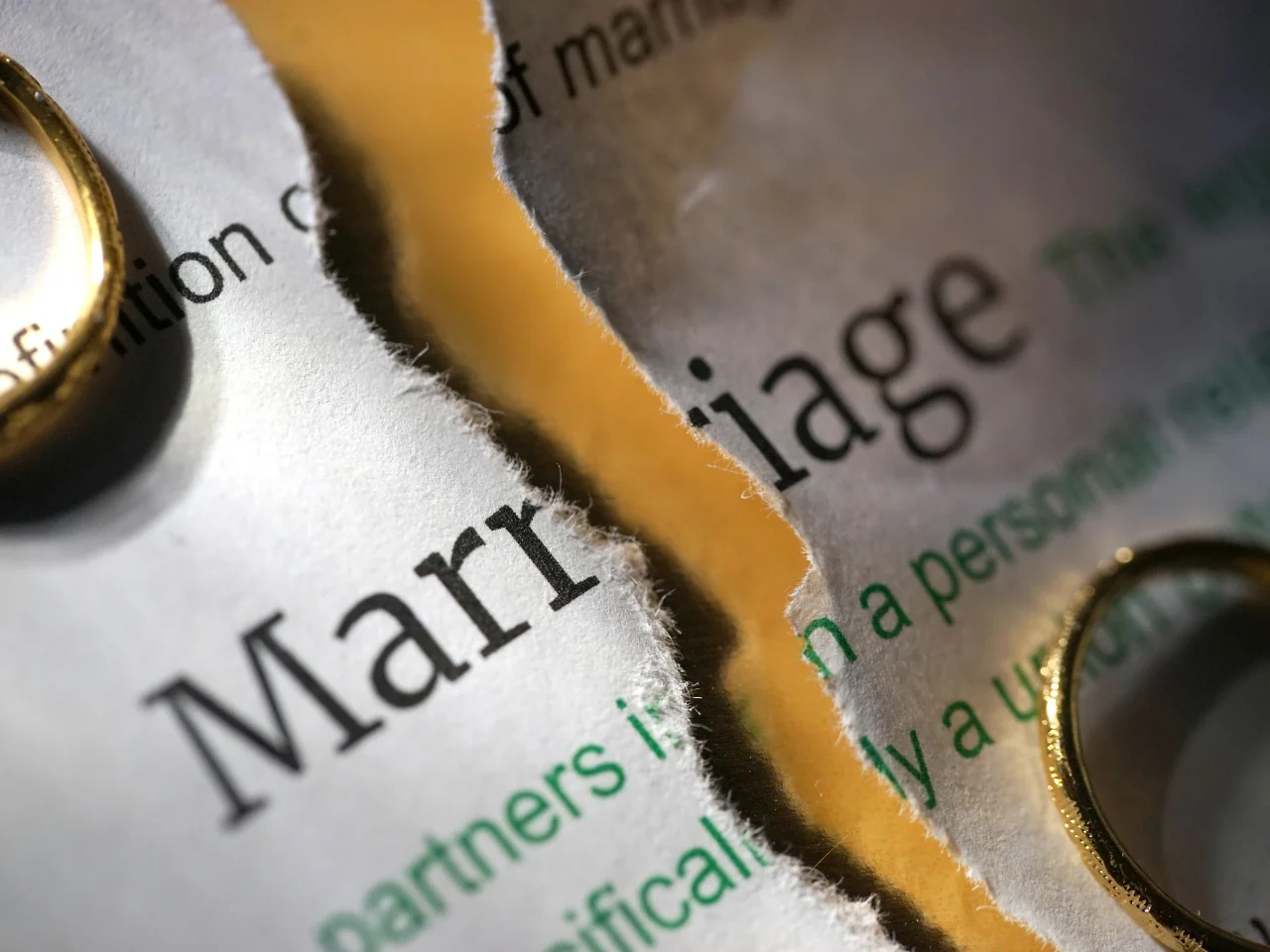 Wedding rings on a torn marriage certificate representing divorce after a marriage performed abroad.