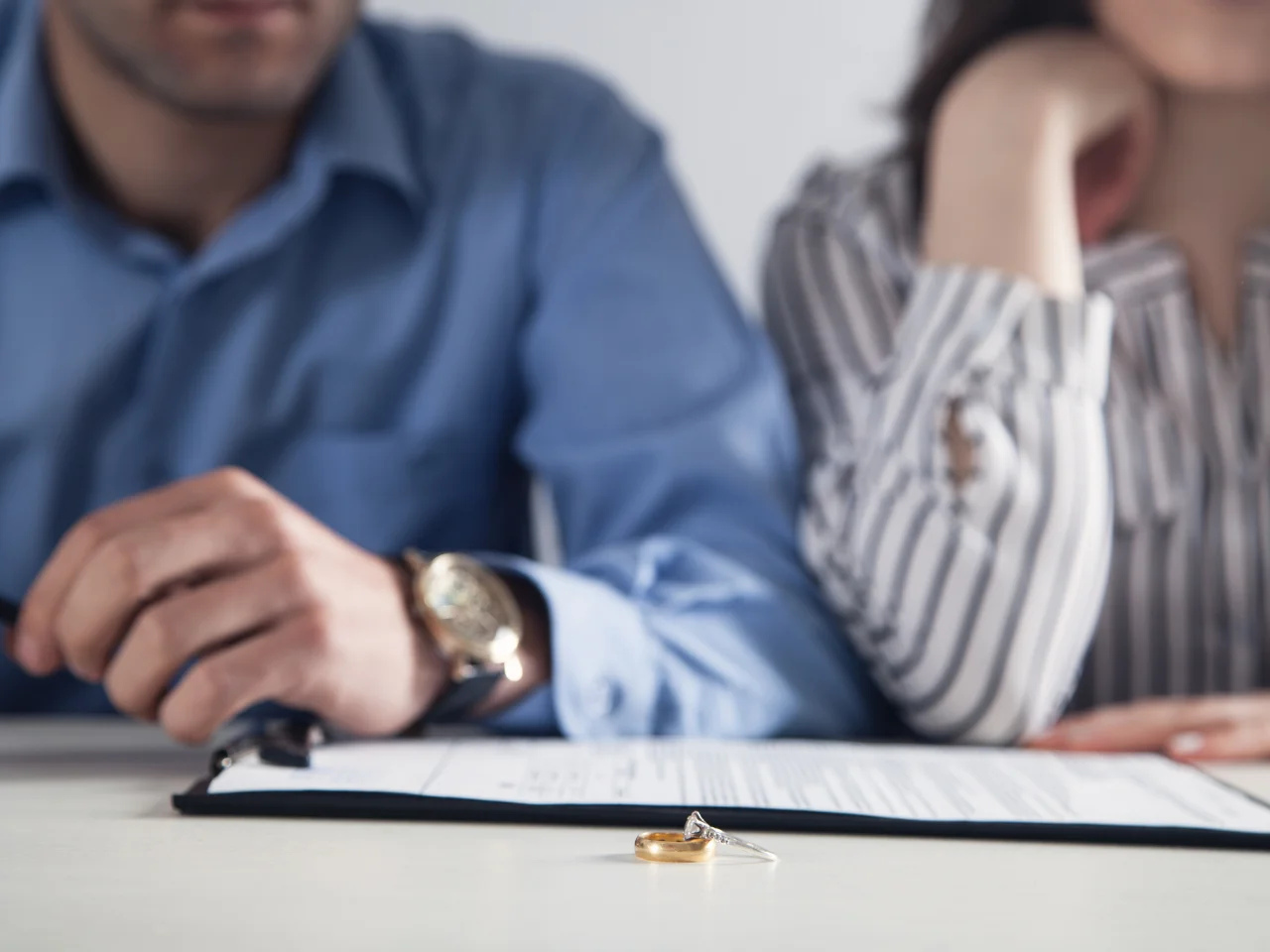 Couple reviewing divorce documents with wedding rings on the table during a legal separation process.