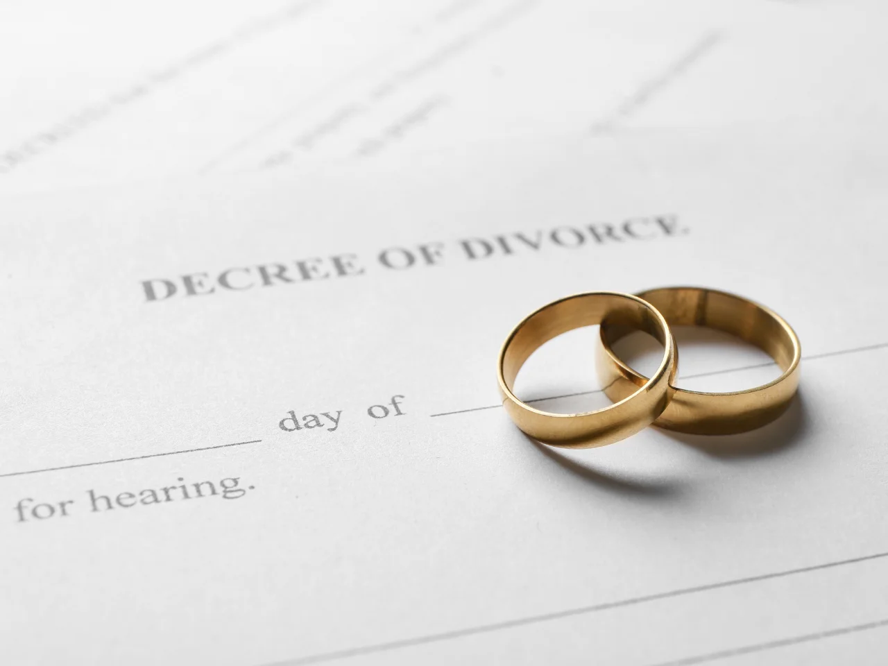 Wedding rings resting on a divorce decree representing the legal completion of a divorce in Canada.