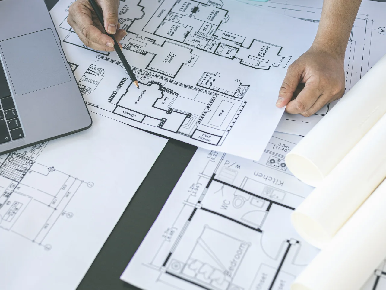 Engineer reviewing architectural drawings and building plans on a desk.